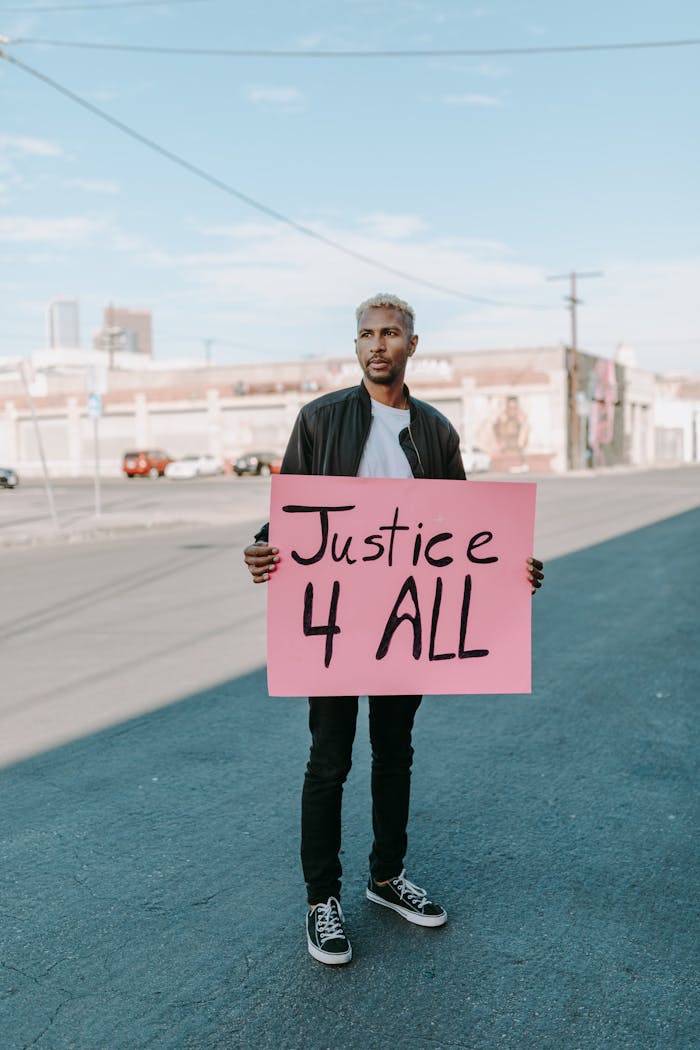 services-03 Man holds 'Justice 4 All' sign during a peaceful outdoor protest.