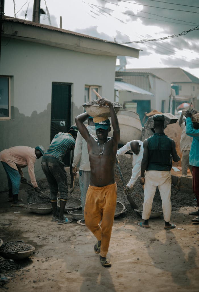 ours-journey Men engaged in intense manual labor at a busy outdoor construction site.