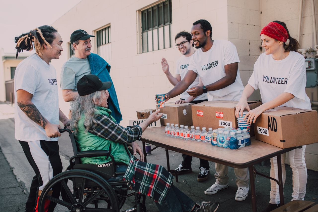 services-02 Volunteers distribute bottled water and supplies to diverse individuals in an outdoor setting, showcasing community support.
